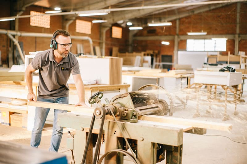 Tischler arbeitet in einer hellen, modernen Werkstatt an einer Maschine