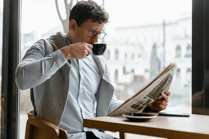 Mann liest am Fenster eine Tageszeitung